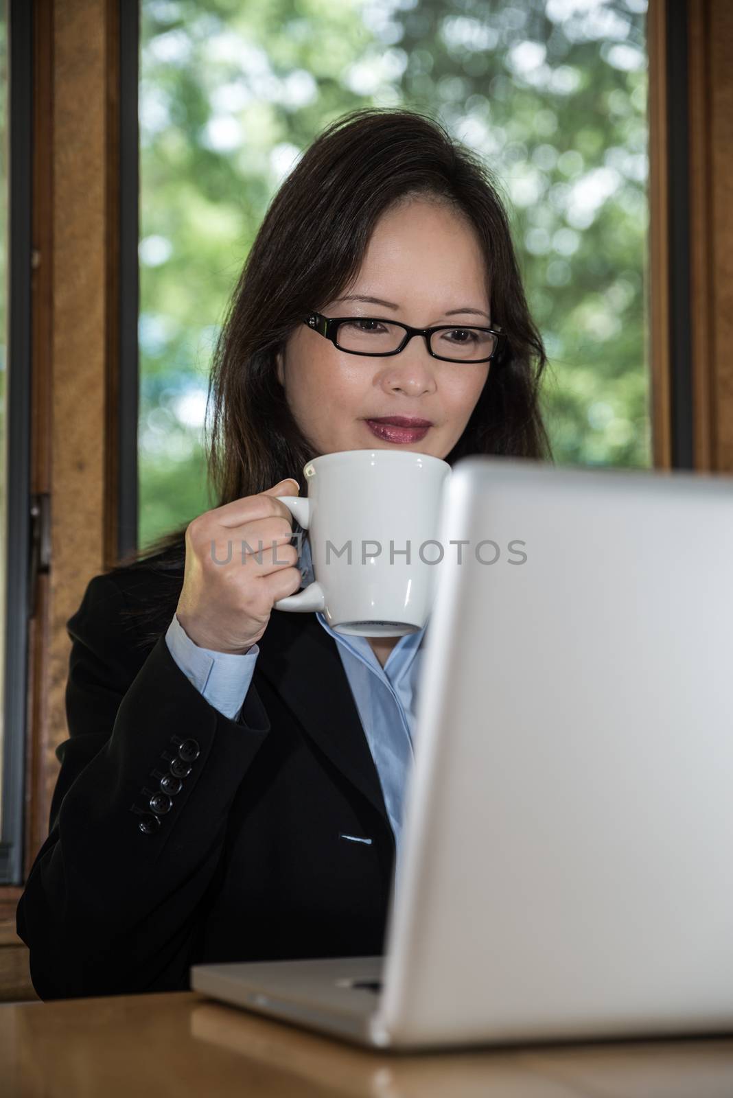 Woman with laptop and coffee by IVYPHOTOS