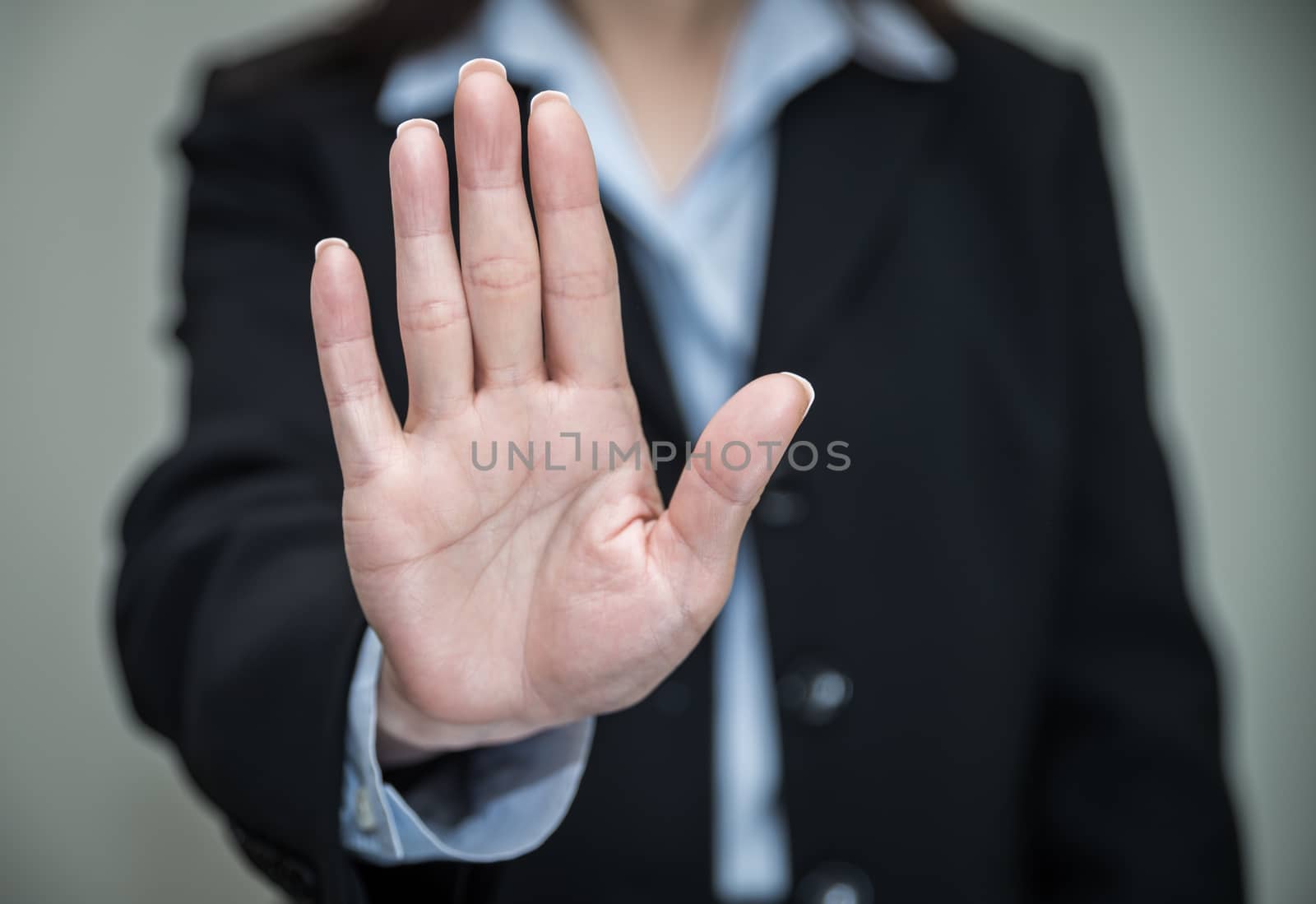 Professional woman in business suit shaking one hand and denying on grey background 