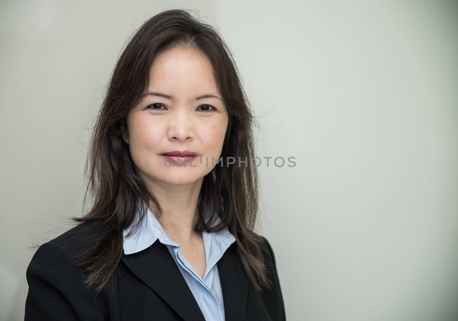 Portrait of professional woman in business suit smiling with grey background 