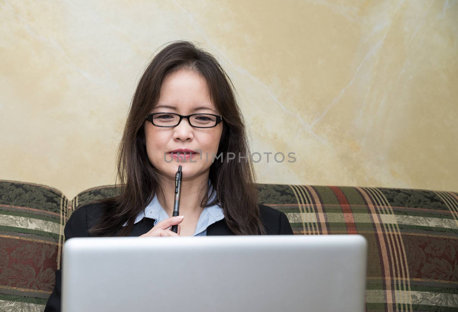 Woman with laptop on sofa by IVYPHOTOS