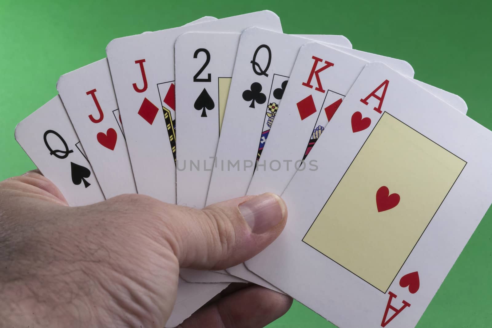 Hand holding a royal flush hearts on green