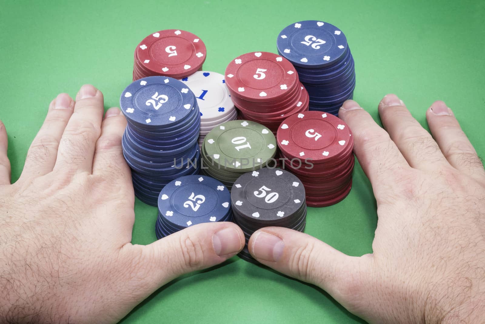 Poker chips and hands above it on green table