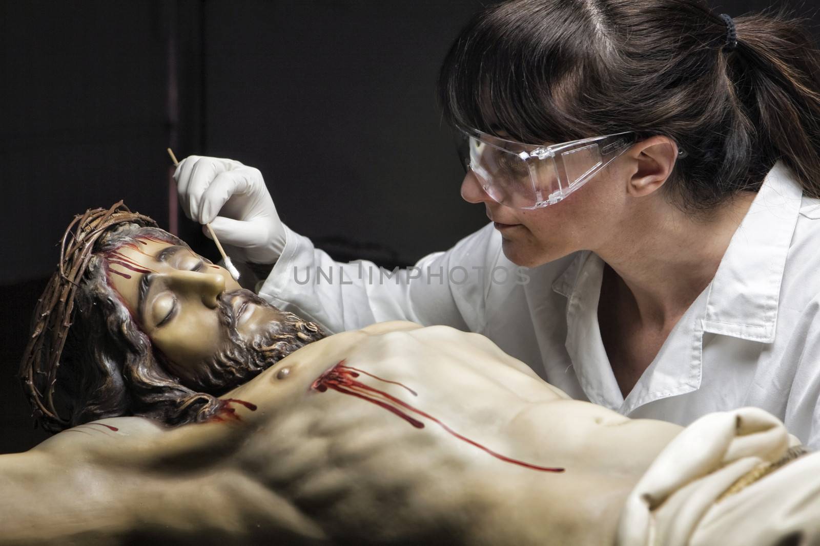 Cleaning of the face of a wooden sculpture of Christ crucified with an isopo impregnated with dimethylformamide, Andalusia, Spain
