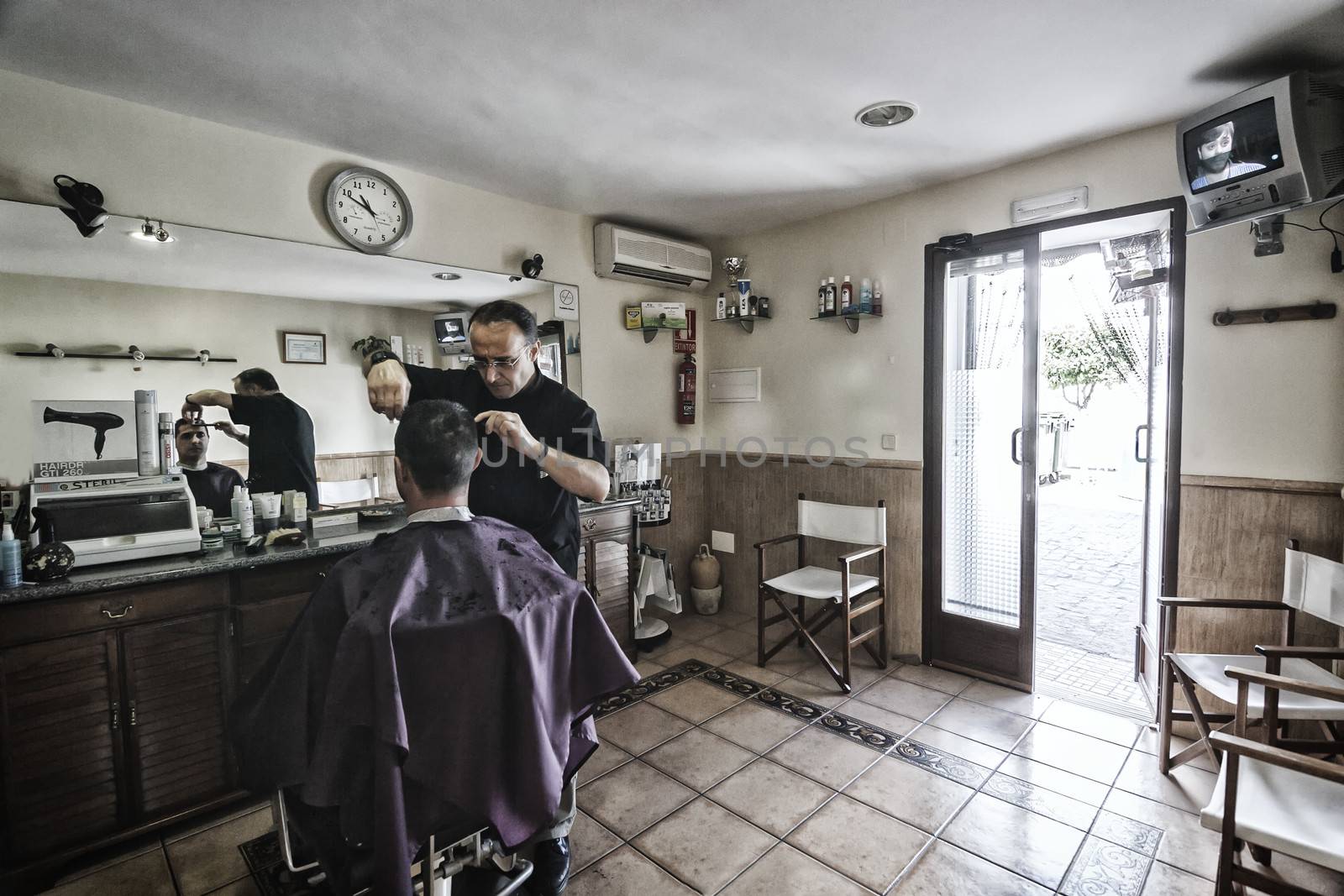 Barber shaving with a razor to young man in a barber's shop, Sabiote, Jaen province, Andalucia, Spain