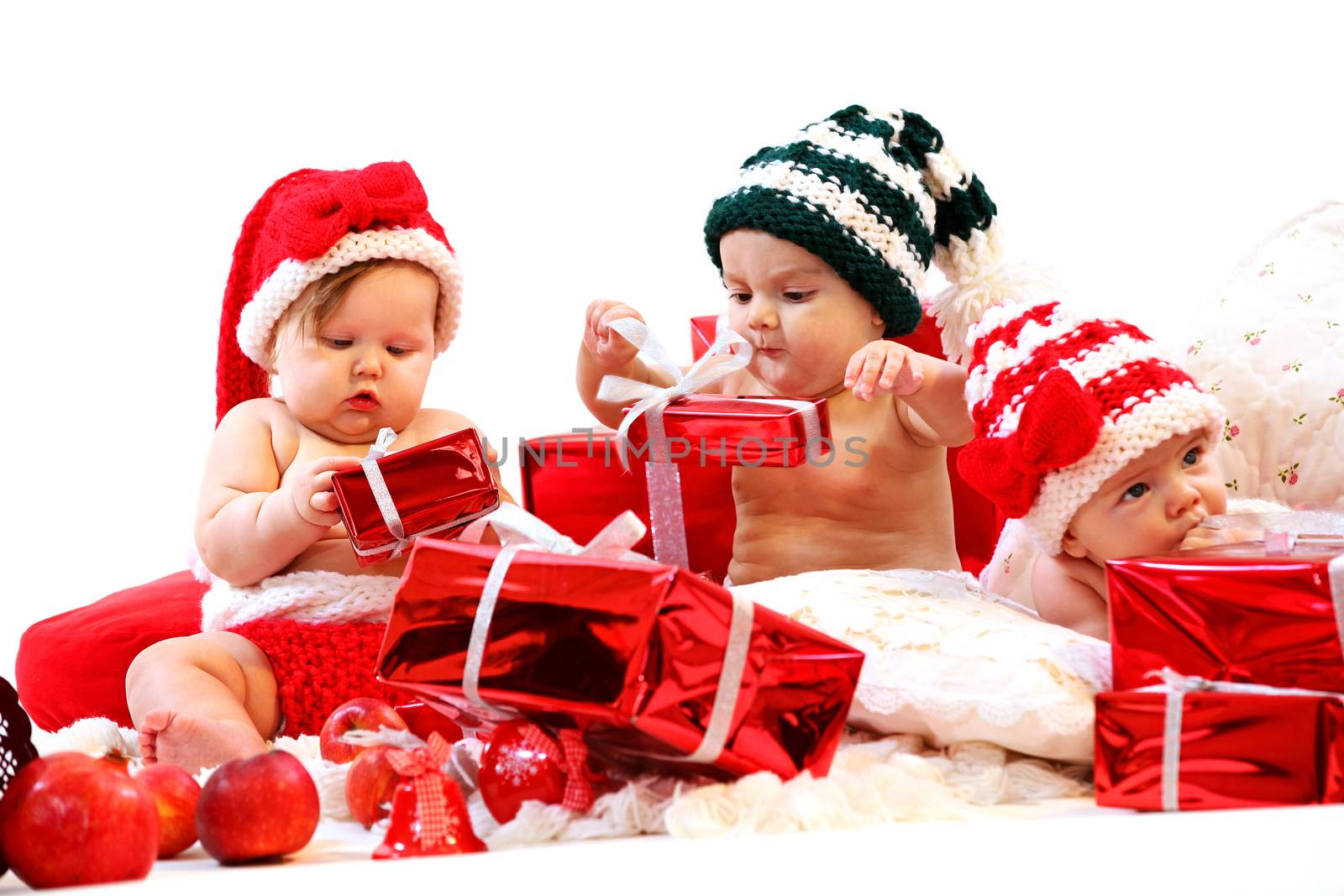 Three babies in xmas costumes playing with gifts over white background