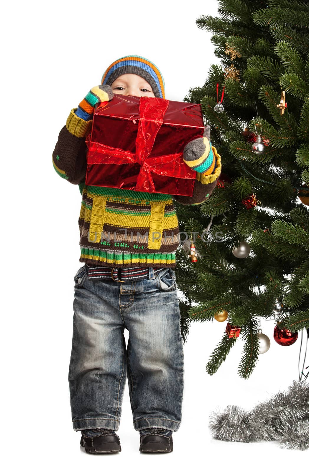 Cute little boy with gift near Christmas tree over white