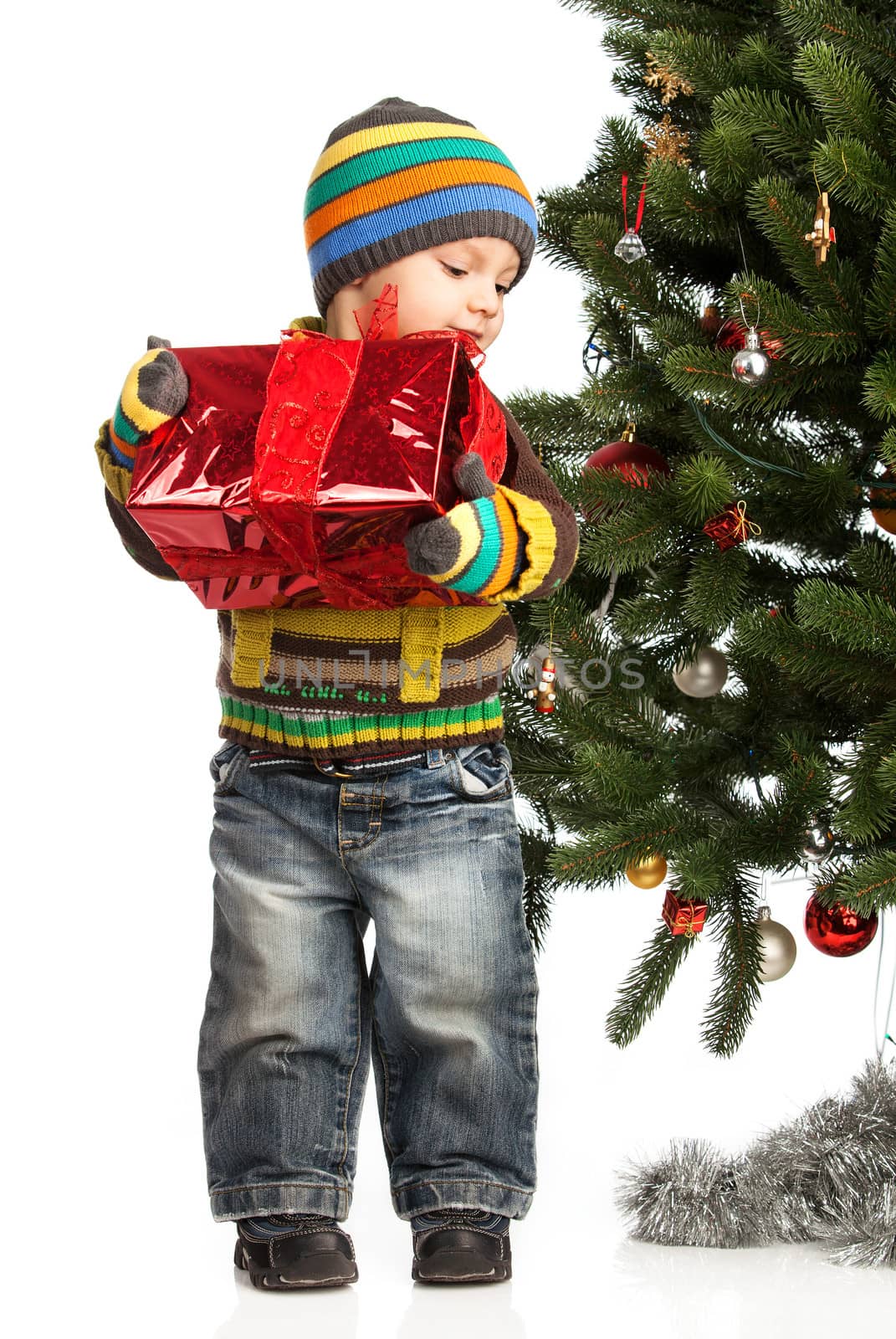 Cute little boy with gift near Christmas tree by photobac