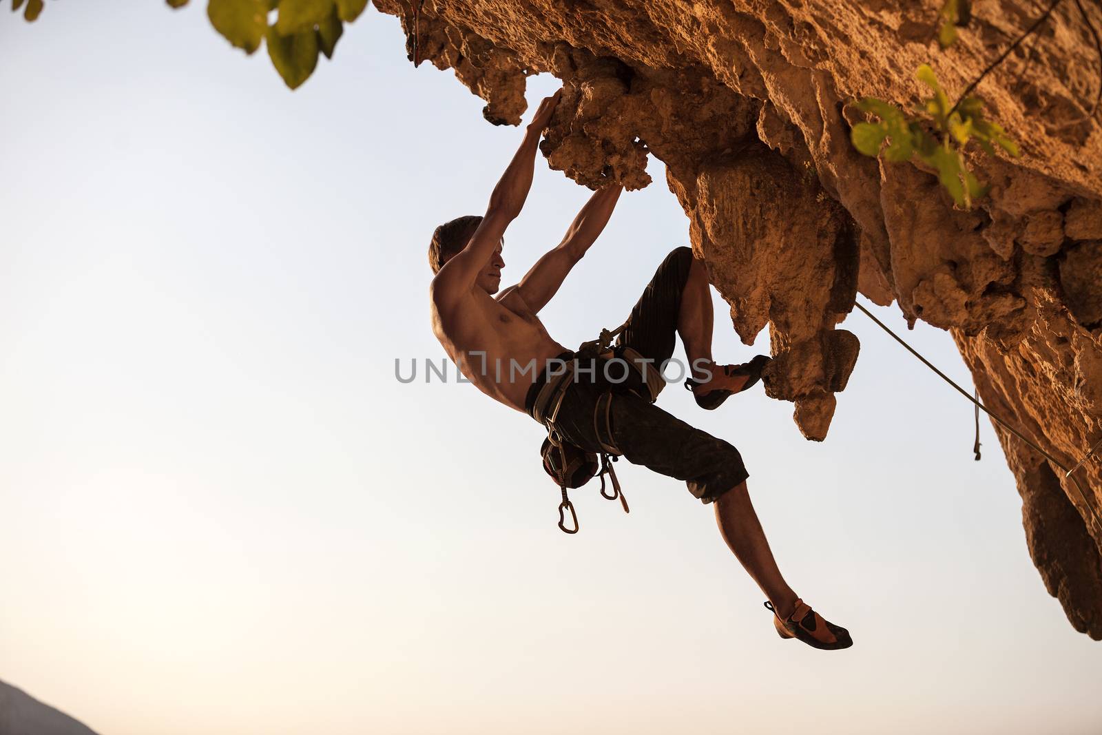 Rock climber of a cliff against sky at sunset