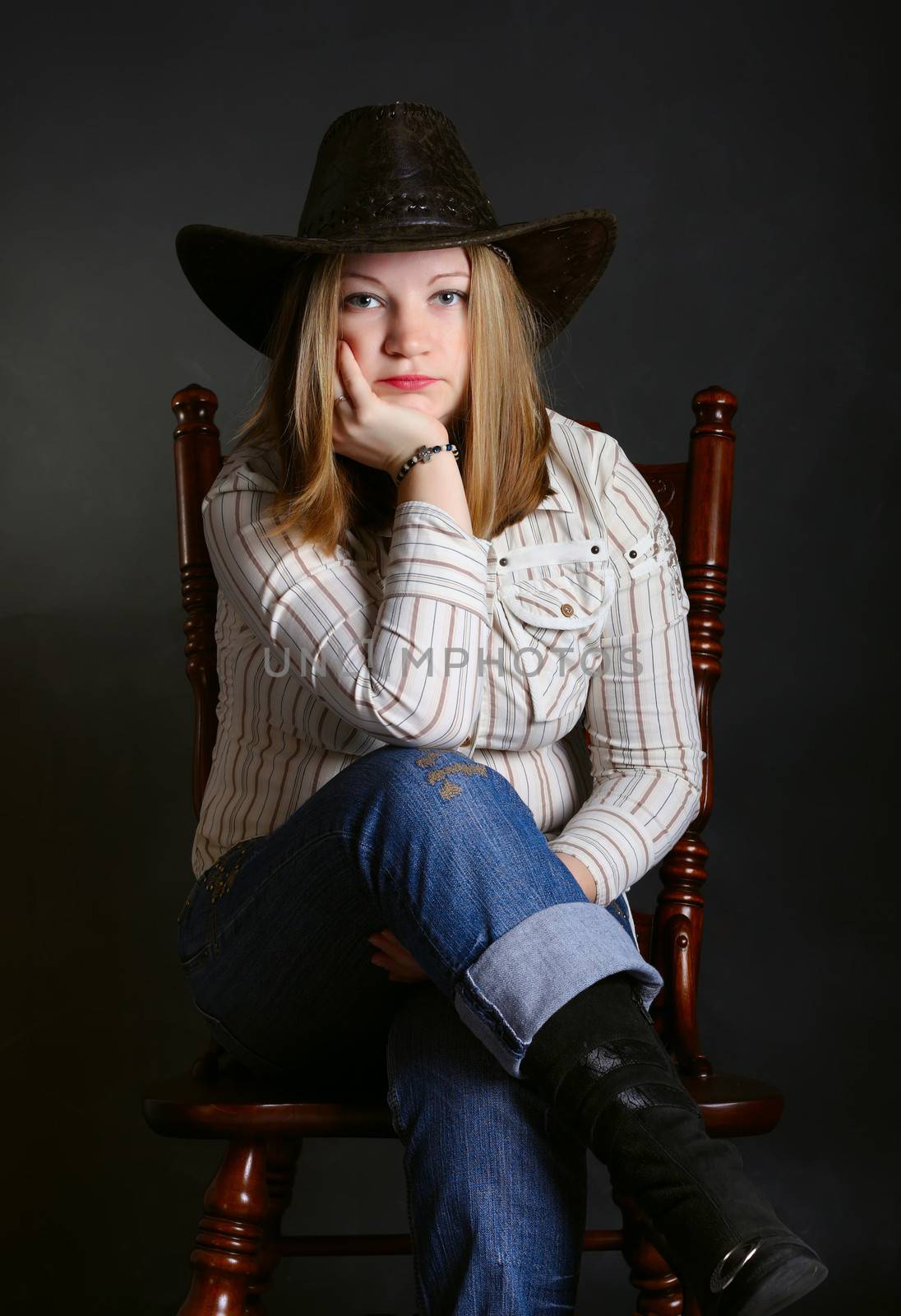 Cowgirl in a jeans sitting on a chair 