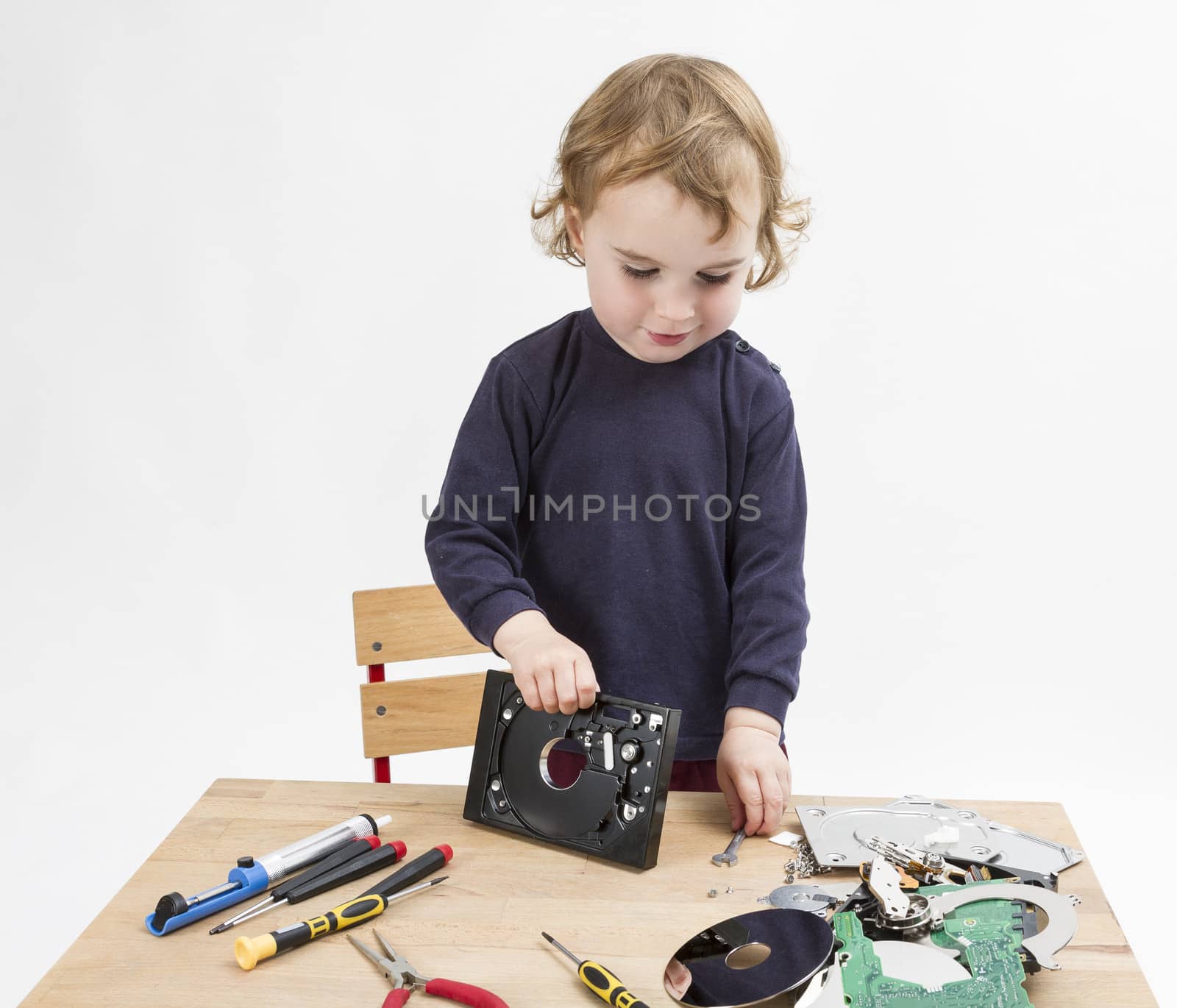preschooler with computer parts on wooden desk. studio shot in light grey background