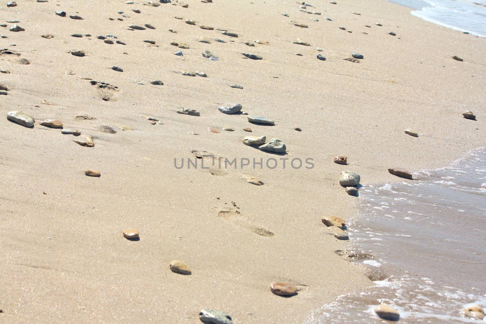 Footprints at the beach among the stones by dedmorozz