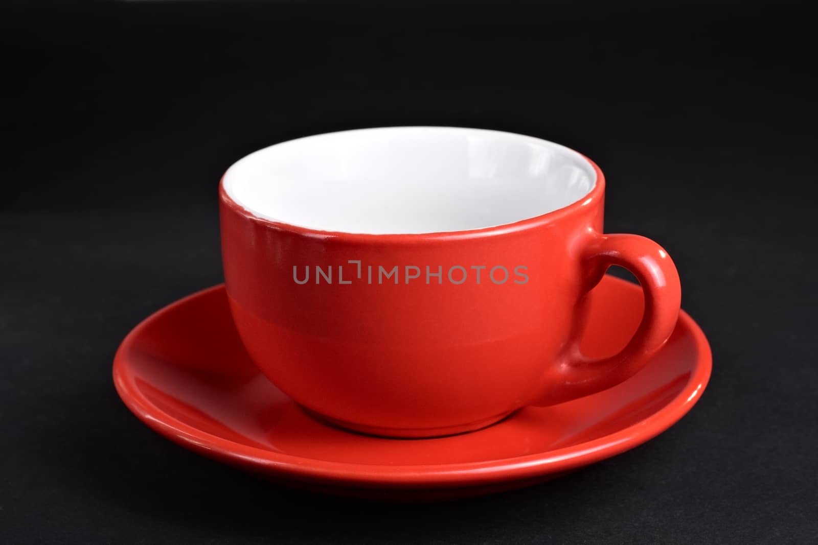 Empty red cup on the plate at the dark background