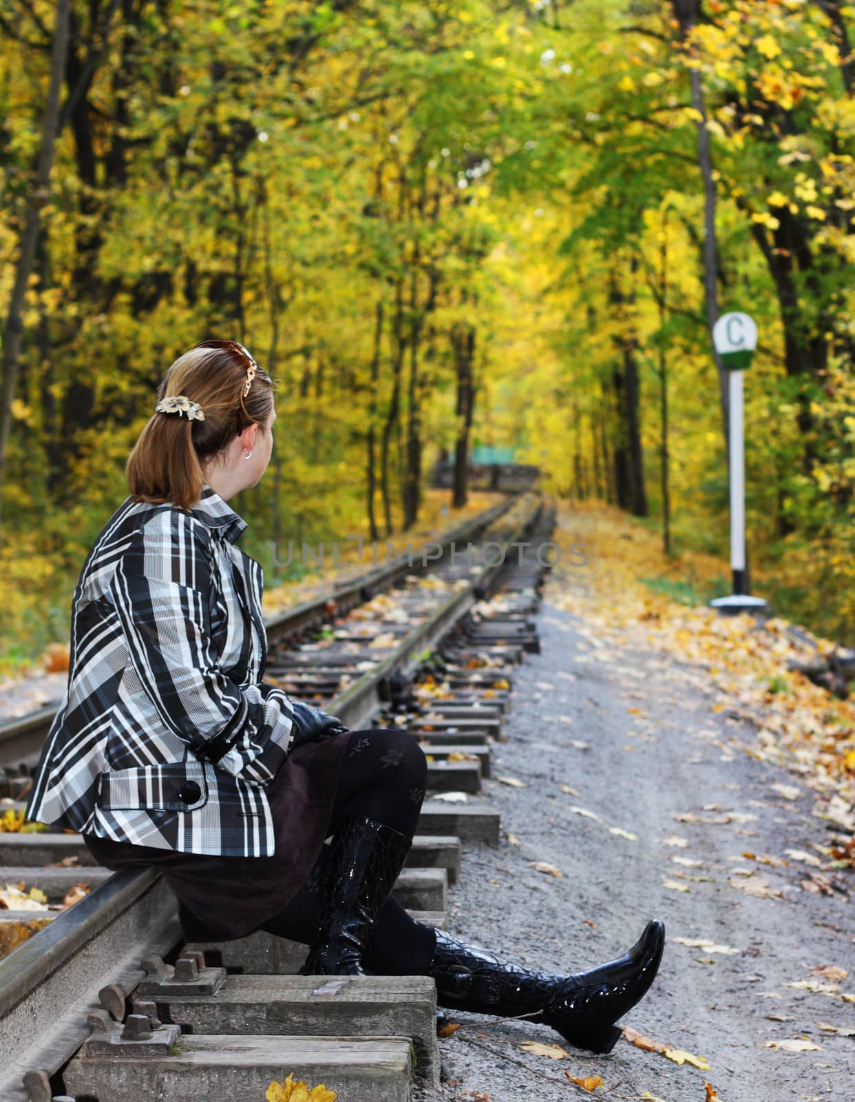 Young women sits on a rails n a autumn forest