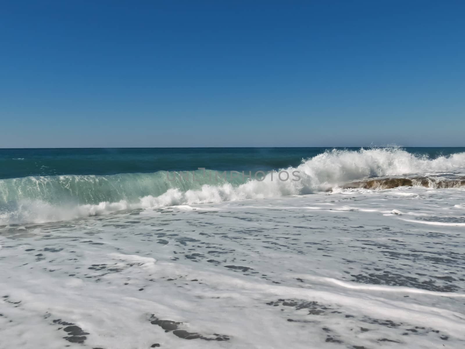Large white foamy wave rolls on the Mediterranean Sea
