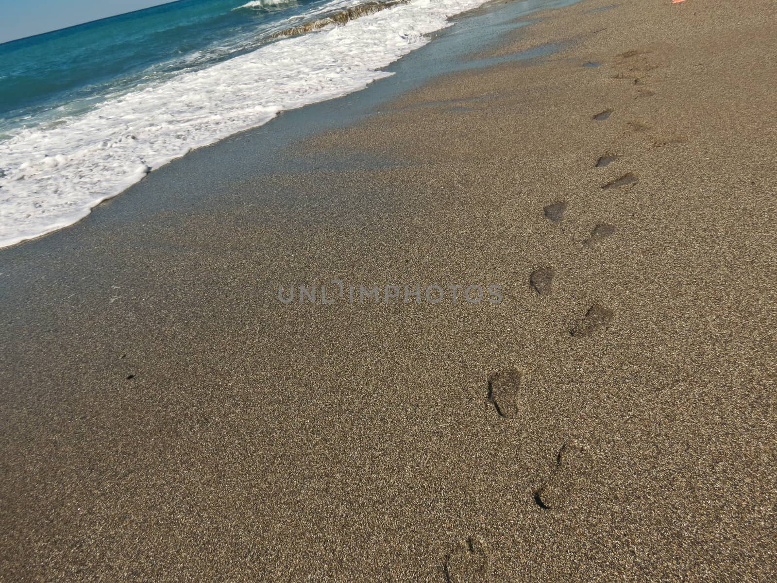 Footprints in wet sand along the coast are