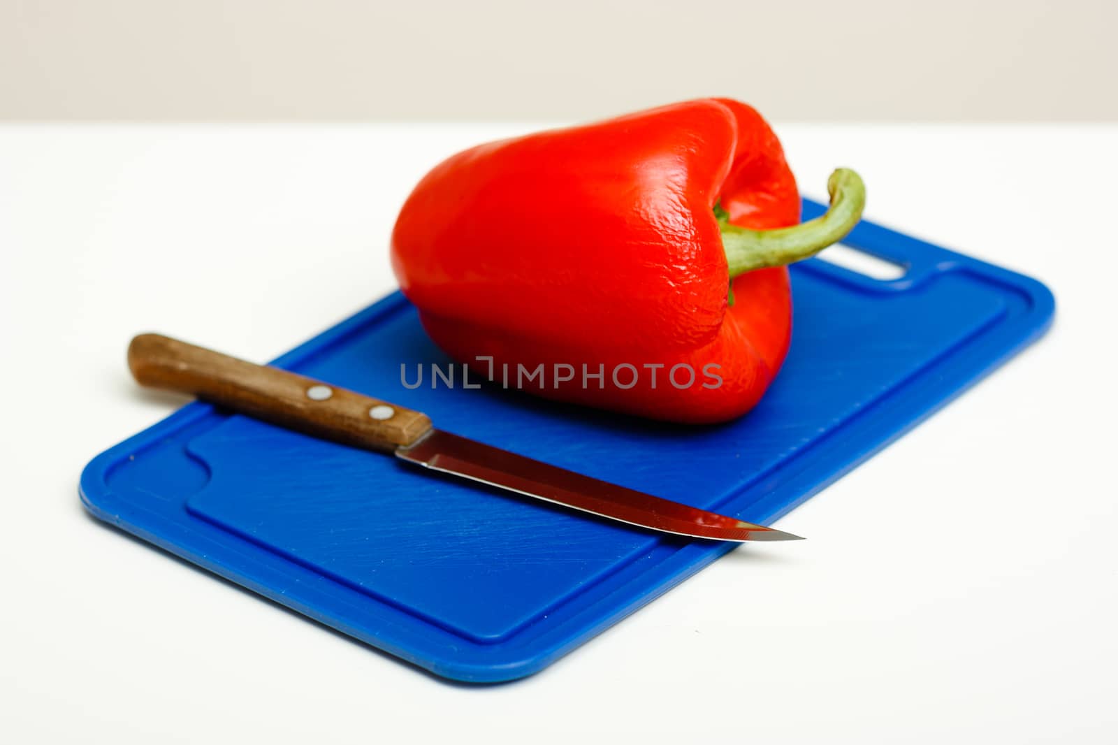 Red pepper and a knife on a cutting board