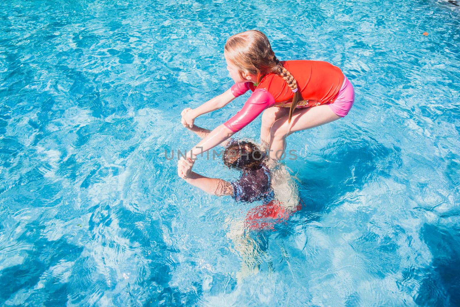 Children brother underwater sister shoulders playing swimming pool outdoors summer