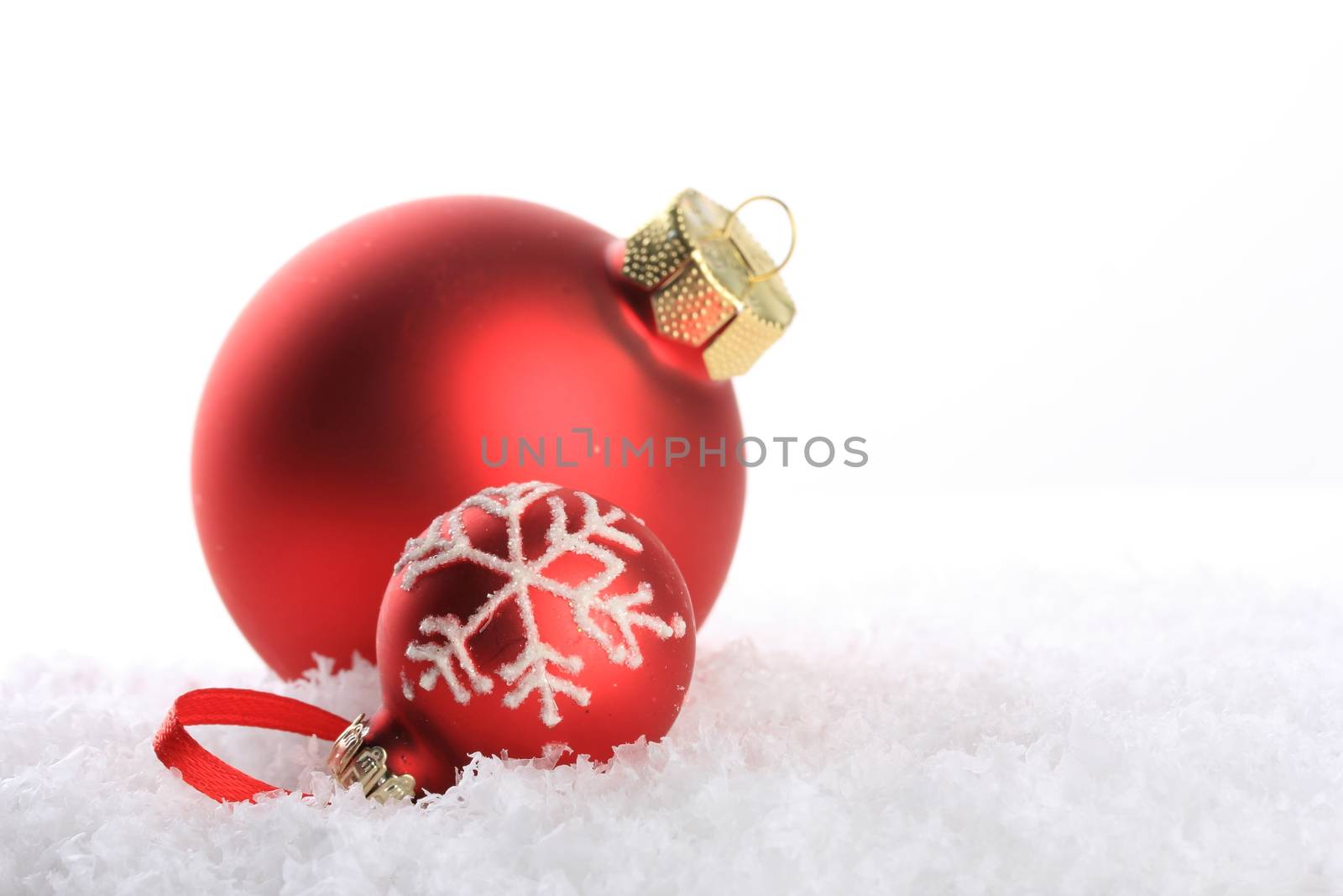 red christmas balls with white pattern on artificial snow 