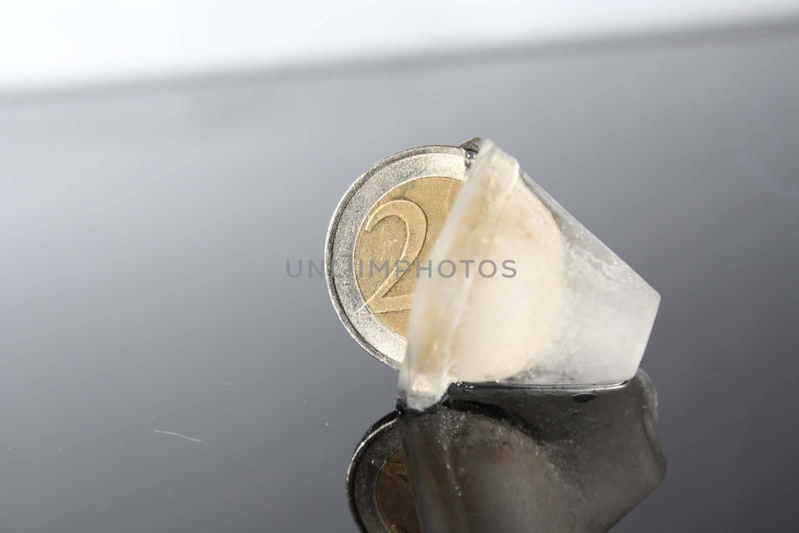 a 2 Euro coin in the ice cube without background