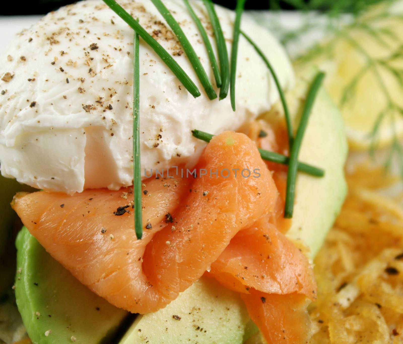 Beautiful salmon and poached egg stack on a hash brown with avocado.
