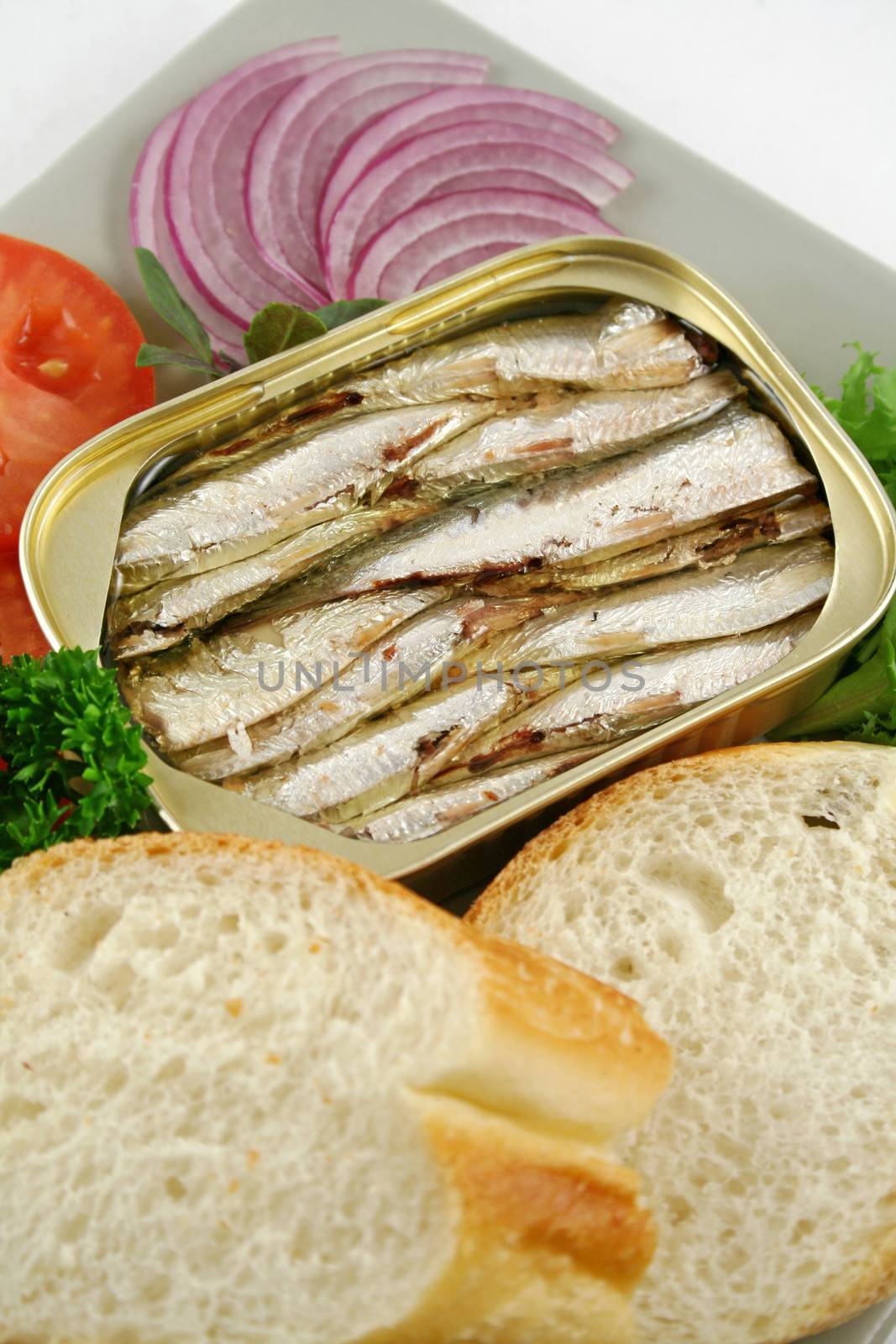 Sardines with bread, red onion, tomato and lettuce.