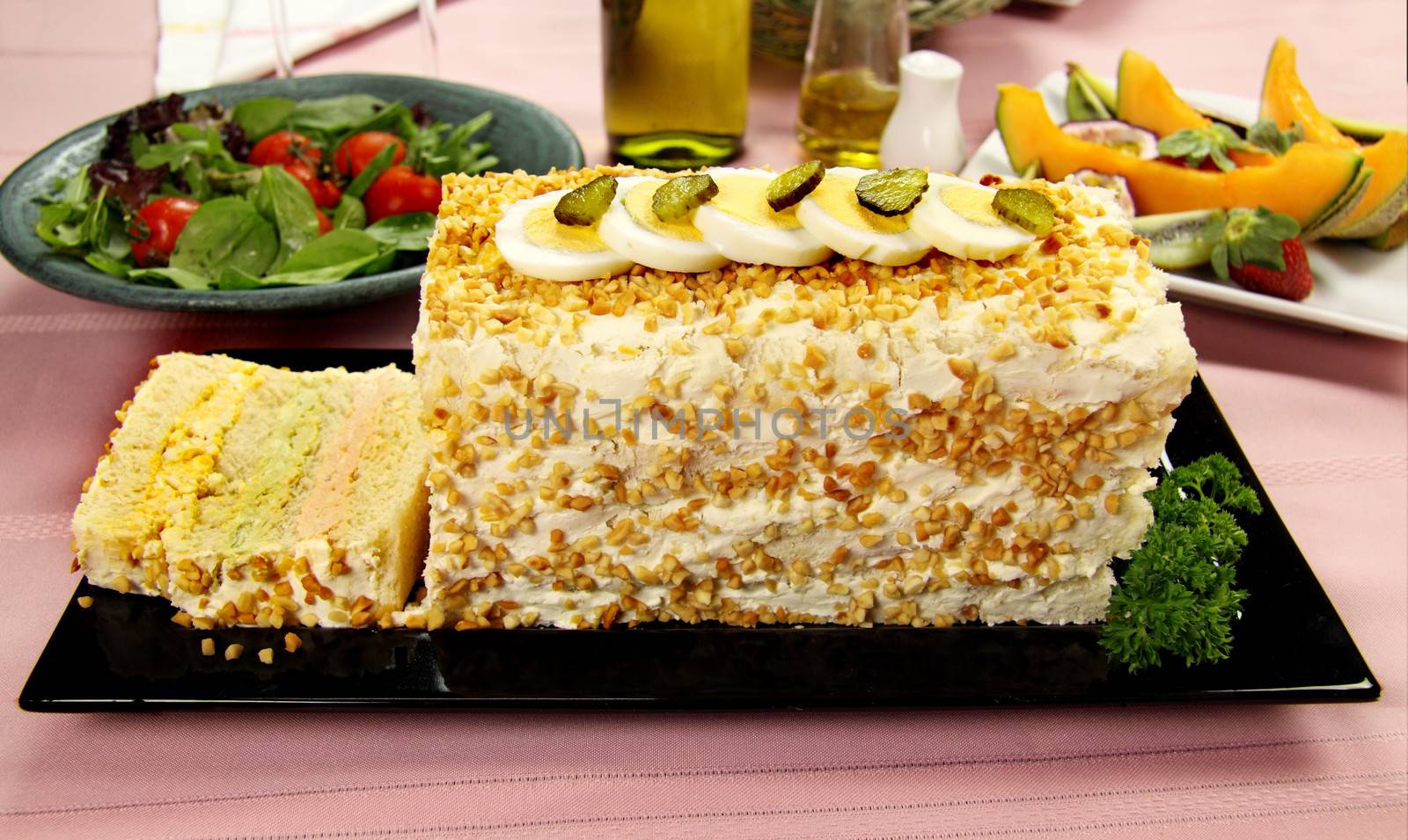 Layered salmon, avocado and curried egg loaf with a fruit platter and salad.