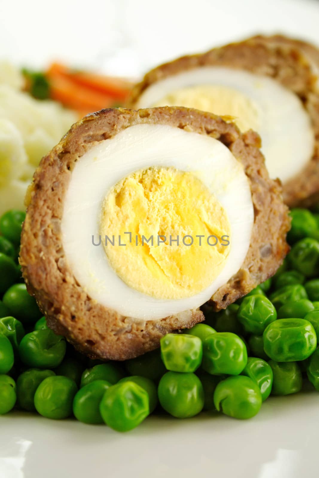 Delicious scotch eggs with peas, carrots and mashed potato.