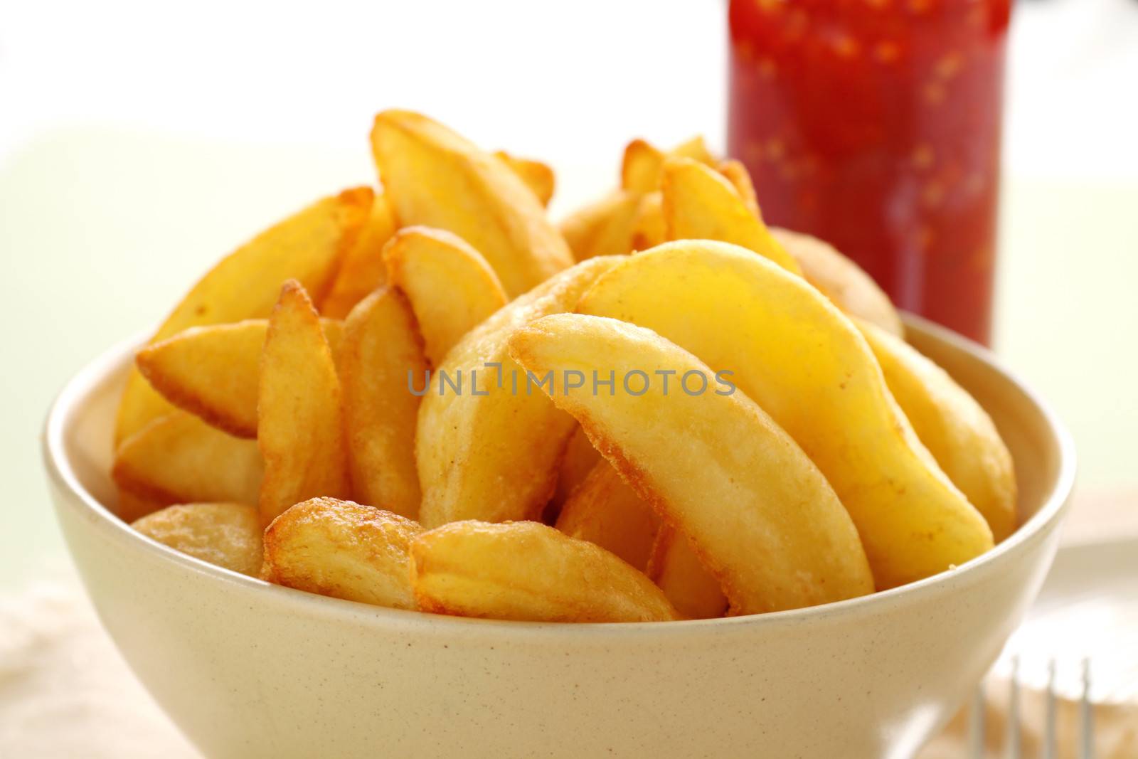 Bowl of freshly fried crisp potato wedges ready to serve.