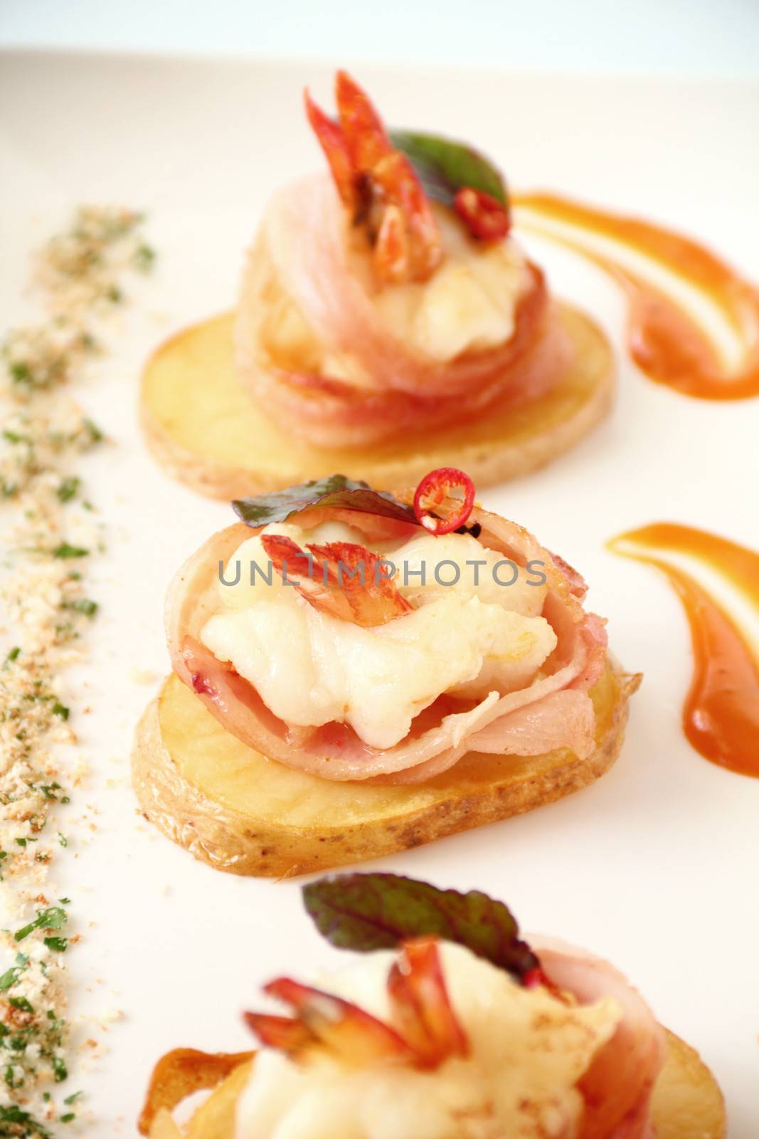 Delicious and delicate shrimps wrapped in bacon on potato slices with a spinach leaf.