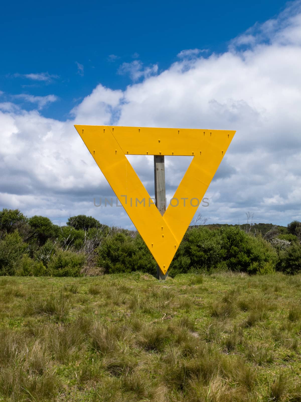 Strange yellow triangle sign on wooden post in coastal countryside landscape used as landmark orientation for shipping navigation