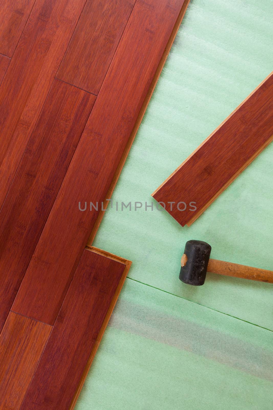 Home improvement construction laying stained brown wooden bamboo hardwood boards flooring and rubber mallet tool