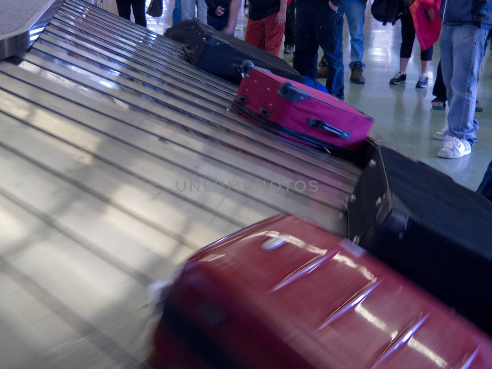 Airport baggage claim, passengers wait for their luggage on conveyor belt after flight landing