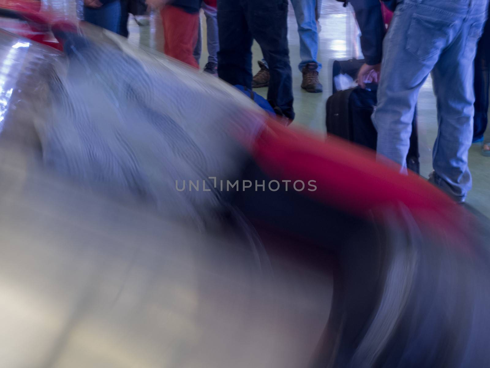 Airport baggage claim, passengers wait for their luggage on conveyor belt after flight landing