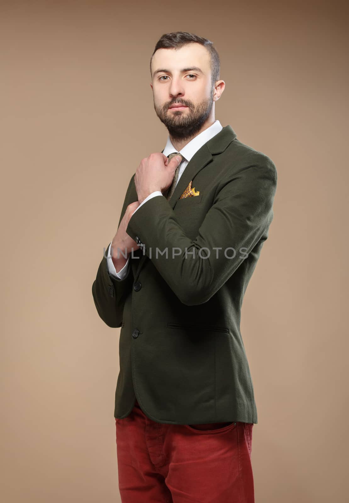 young man in a green suit and tie, beige background