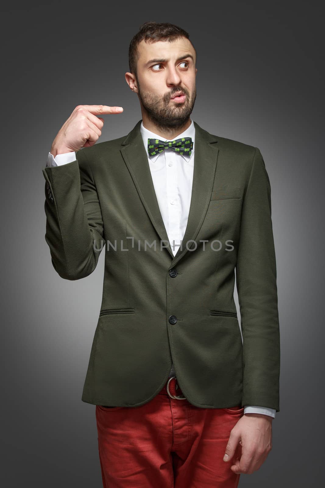 young man in a green suit, pointing at the right