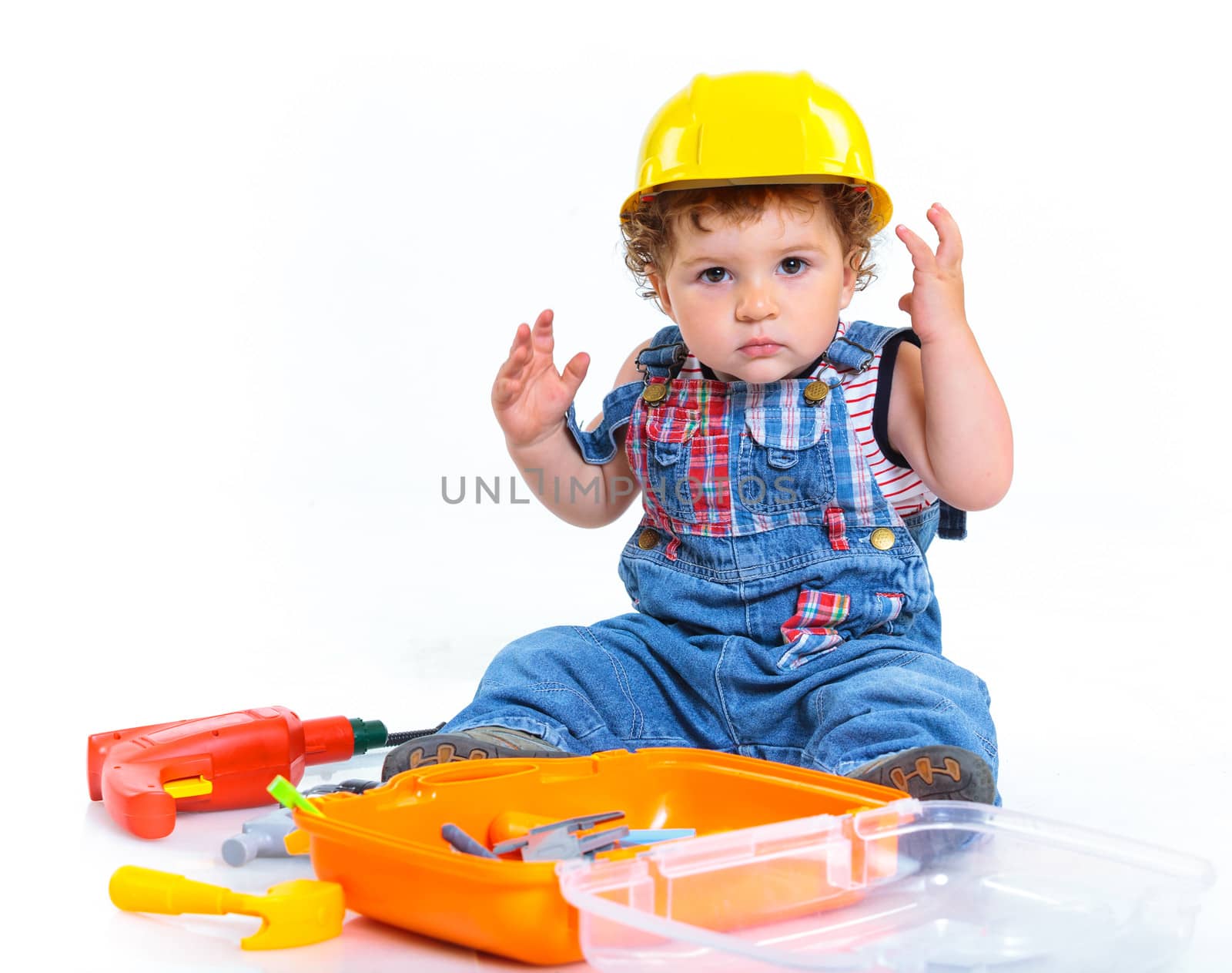 Little builder. Baby boy in a helmet plays in the builder with tools. Isolated over white.