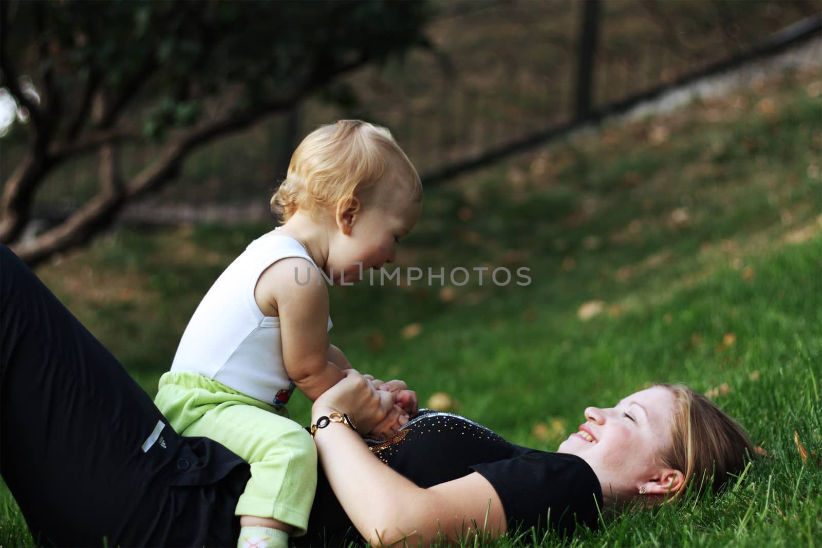 Mother with her son play on a green grass