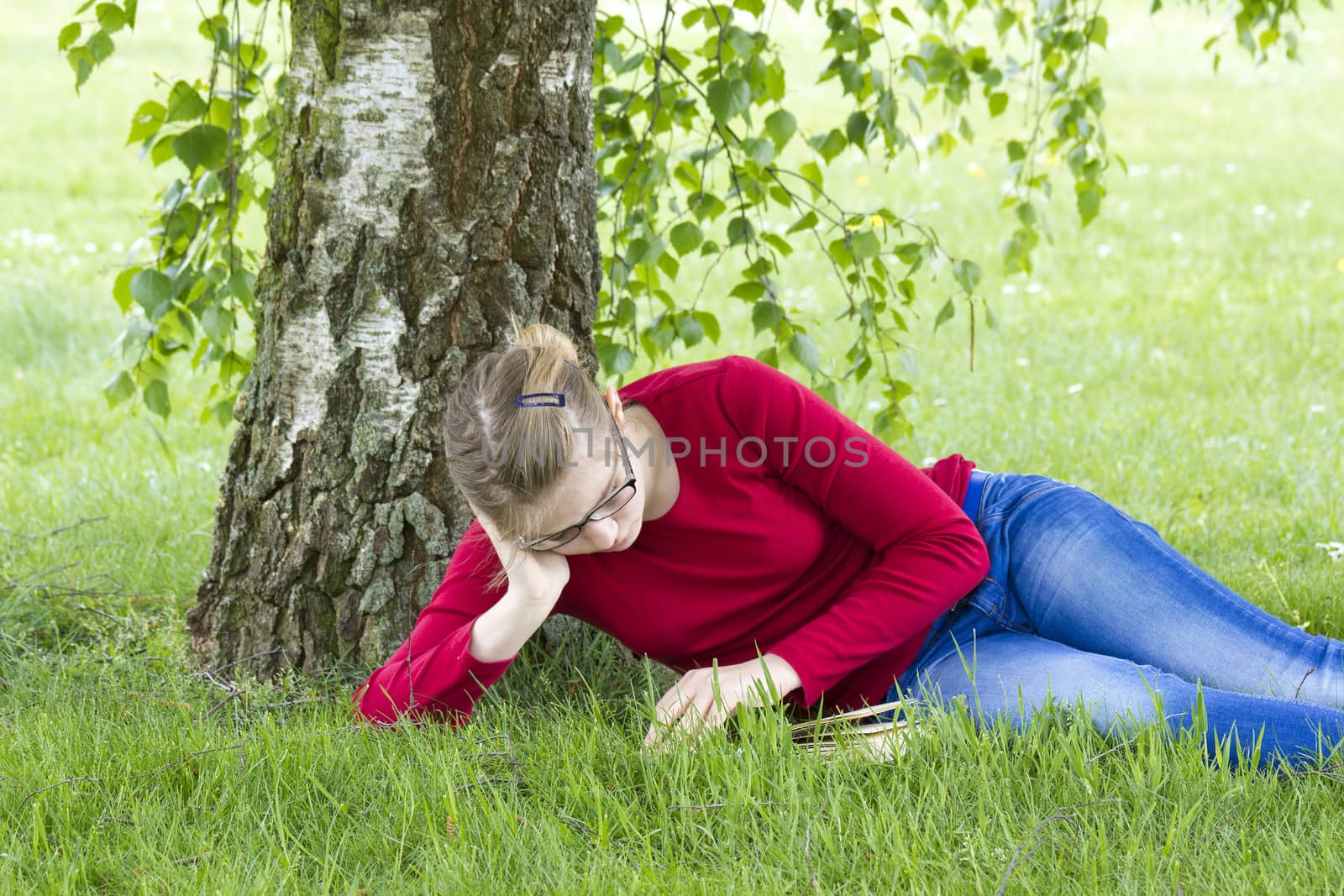 Young girl reading book in park in spring day by miradrozdowski