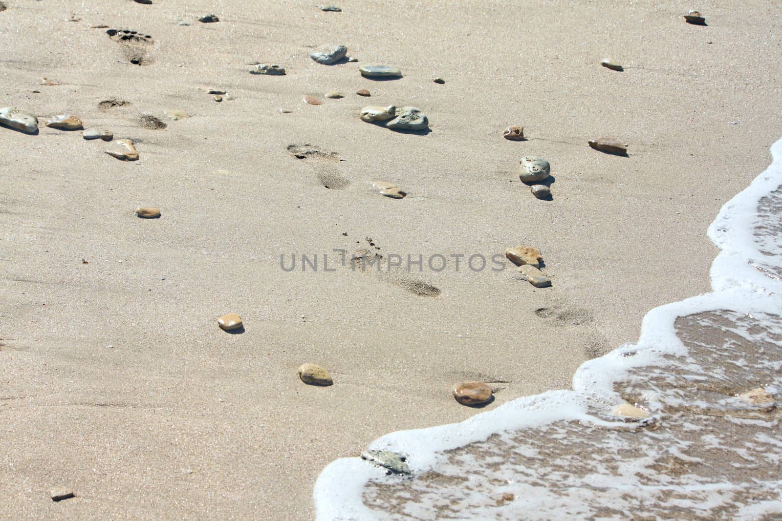 Footprints at the beach among the stones by dedmorozz