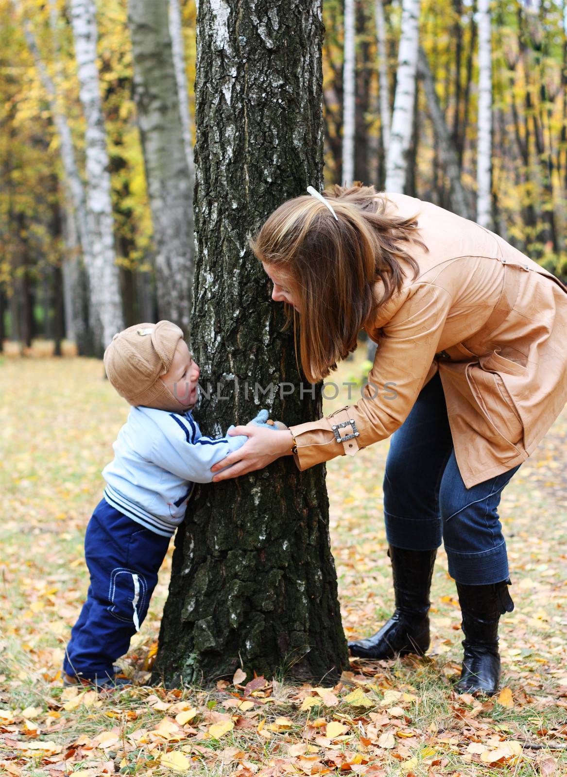 Mother with son play seek and hide in a park