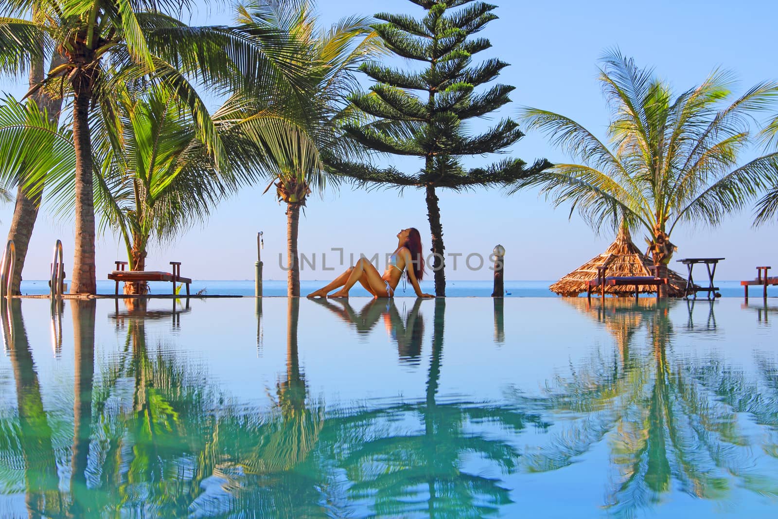 Beautiful woman near swimming pool on tropical beach