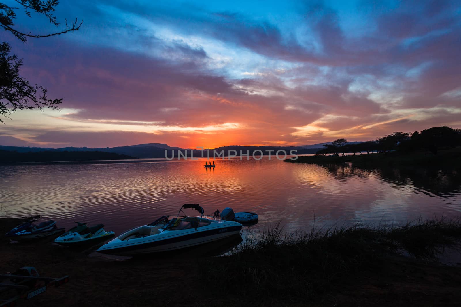 Dawn morning color reflections in sky clouds reflections on boats by dam lake waters