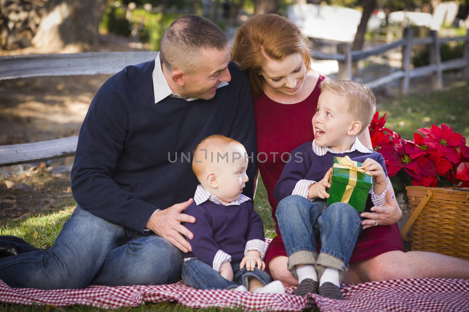 Beautiful Small Young Family Opening Christmas Gifts in the Park.