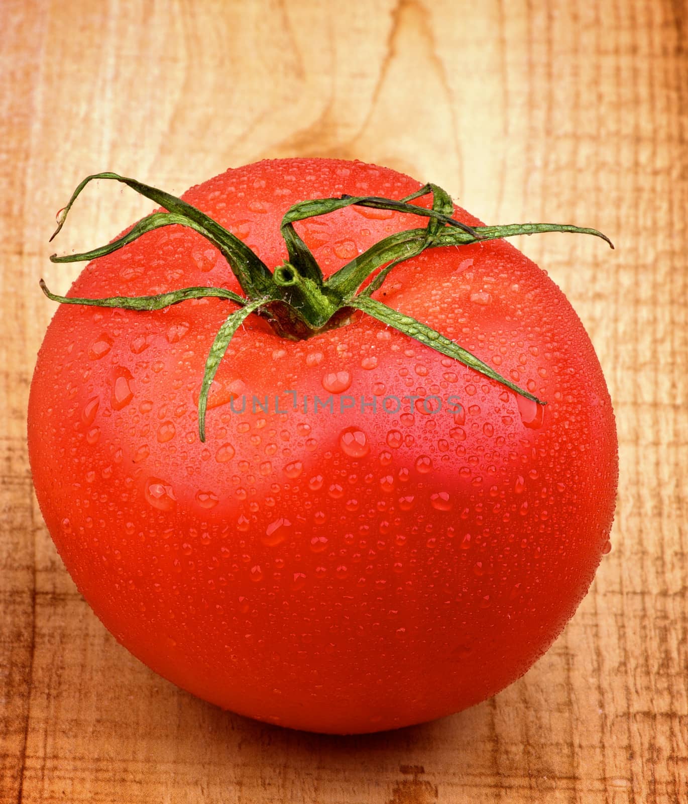 Big Ripe Tomato with Water Drops closeup on Rustic Wooden background