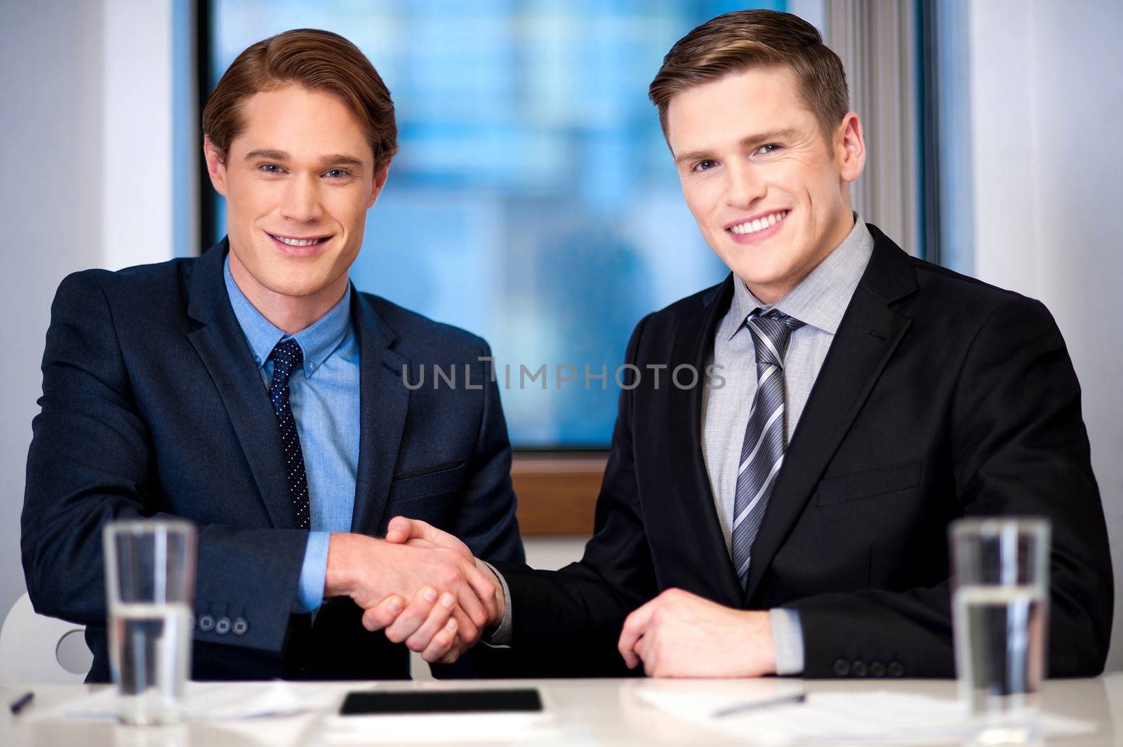 Corporate guys shaking hands by stockyimages