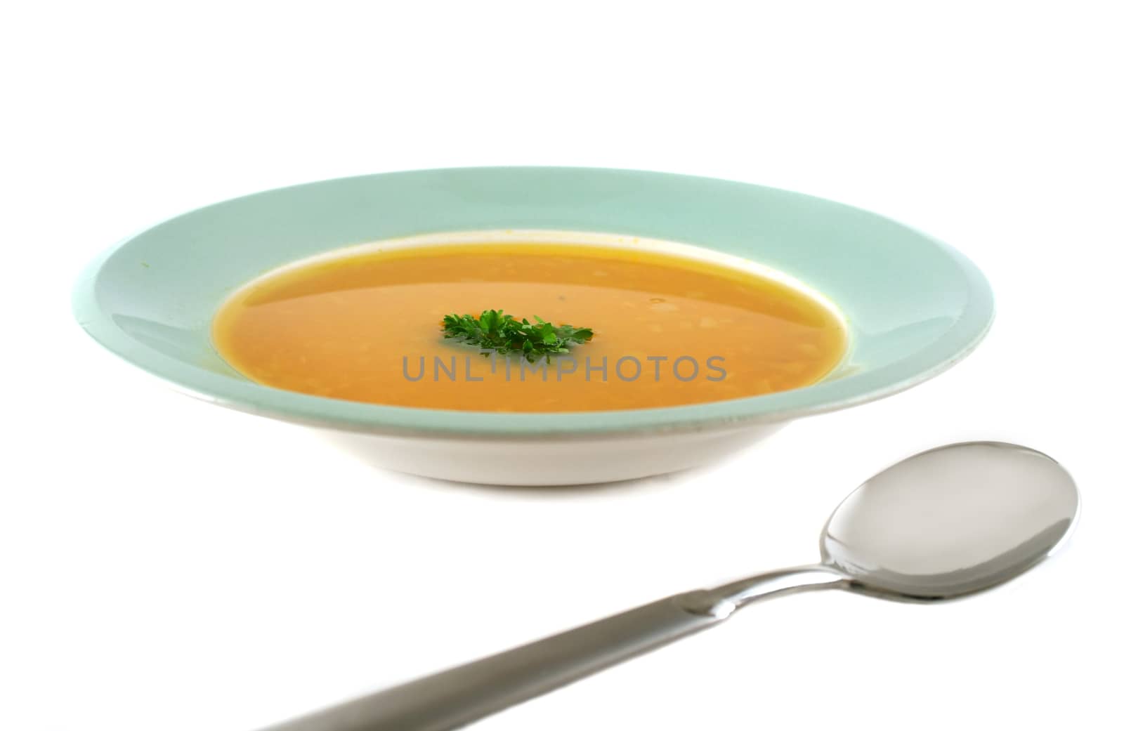 Profile view of pumpkin soup with parsley and spoon.