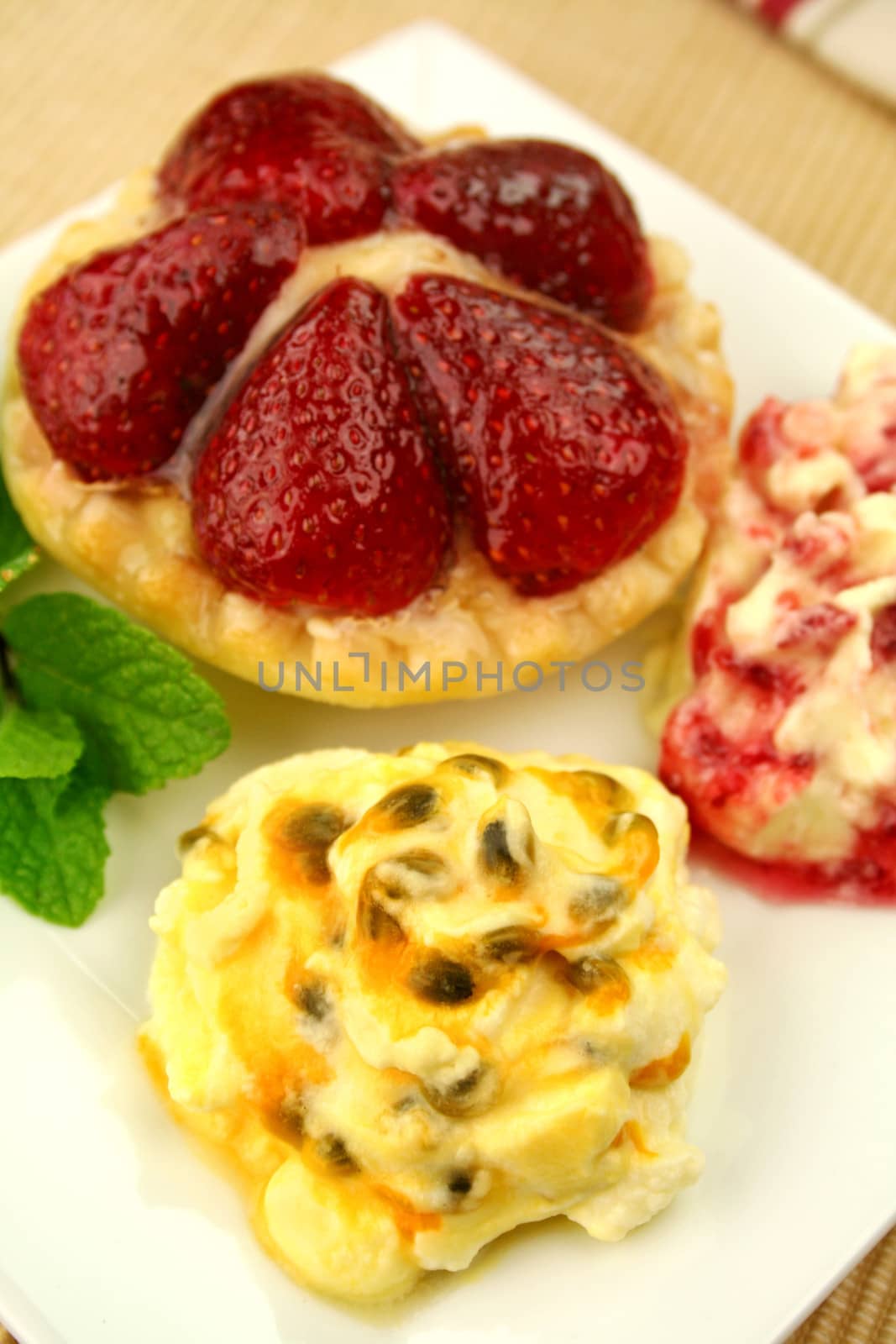 Strawberry custard tart with passionfruit cream and cranberry cream with a mint garnish.