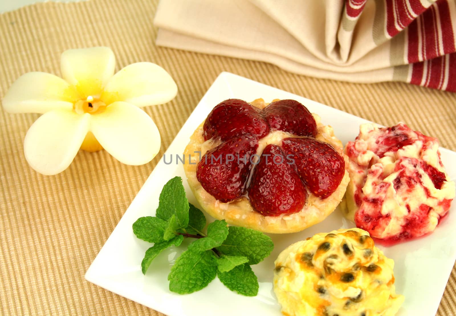 Strawberry custard tart with passionfruit cream and cranberry cream with a mint garnish.