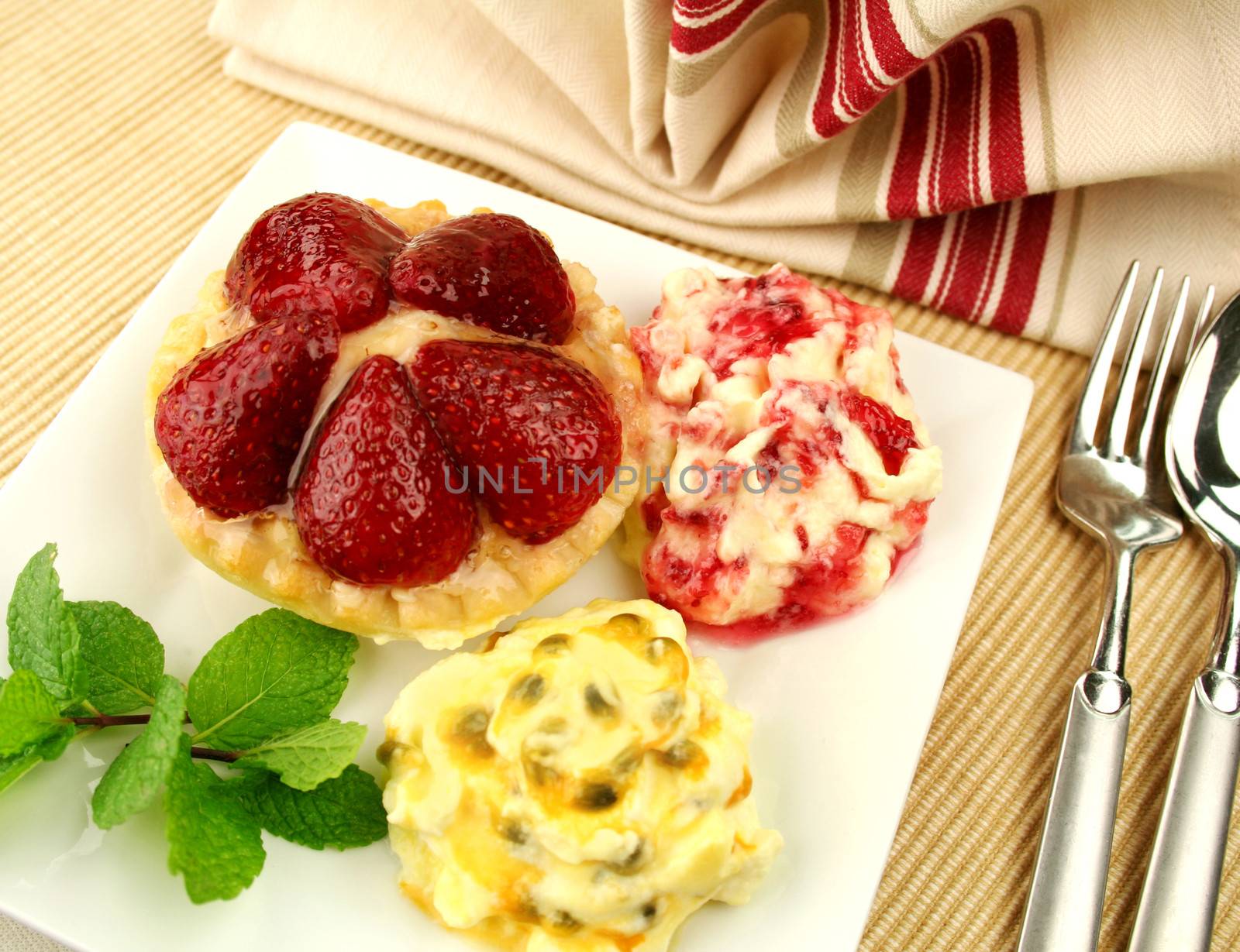 Strawberry custard tart with passionfruit cream and cranberry cream with a mint garnish.