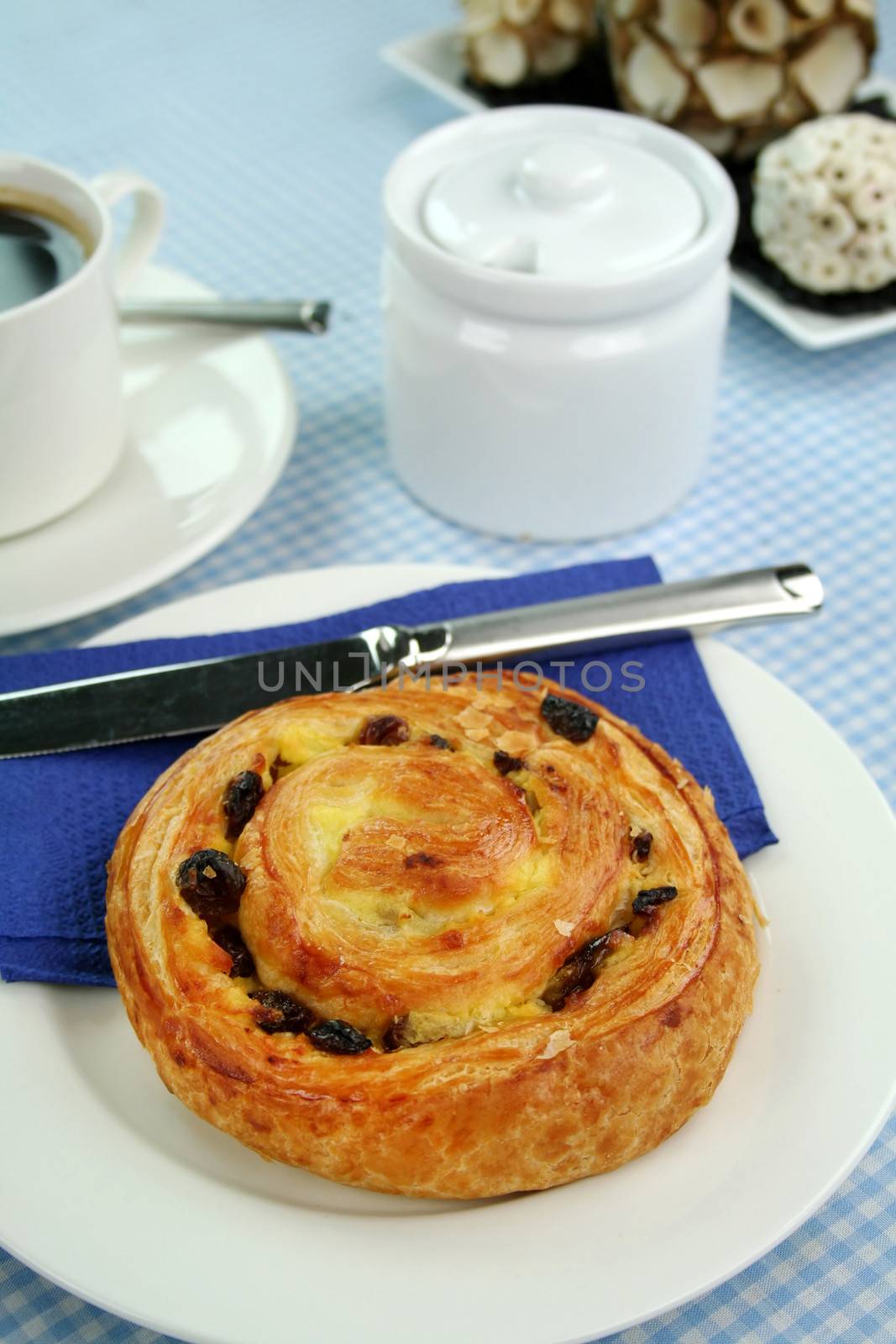 Delicious sultana danish pastry with a cup of black coffee and sugar.